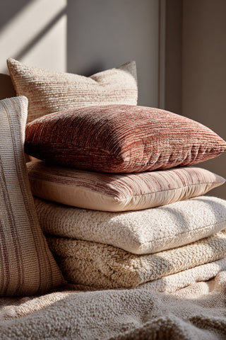 Multiple throw pillows in varying colors of neutrals and textures such as velvet, boucle, linen and cotton