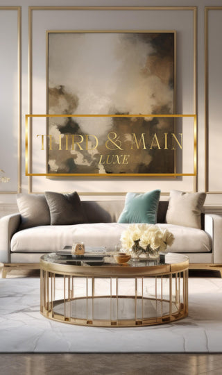A sophisticated luxury decor style living room in neutral colors with a luxe sofa, velvet throw pillows, a coffee table and a large beautiful piece of art on the wall