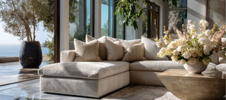 Luxury modern Malibu living room styled with the Luxe Curated Decor Collection from Third & Main, featuring sculptural neutral furniture, refined stone accents, and an elegant floral arrangement in natural light