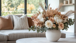 Fall Colored large Floral Arrangement styled on a coffee table i a luxury contemporary decor style living room, The flowers are mixed with pampas, hydrangea, roses in mauve and cream and greenery