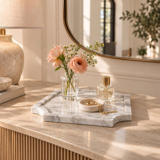 Medium 10.25-inch natural Volakas marble tray with gray veining and sculpted edges, styled on a console with a crystal bud vase, perfume bottle, and small jewelry dish.