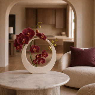 11-inch creamy white sand-glazed stoneware sculpture styled with burgundy orchids on a round marble table in a warm modern transitional living room.