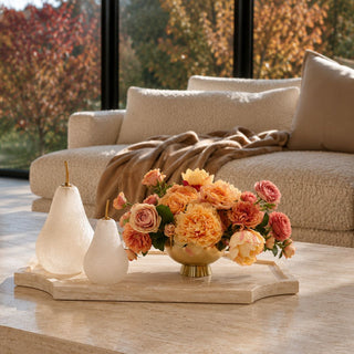 14 Inch white travertine stone tray styled on a living room coffee table with decorative pears and a warm floral arrangement.