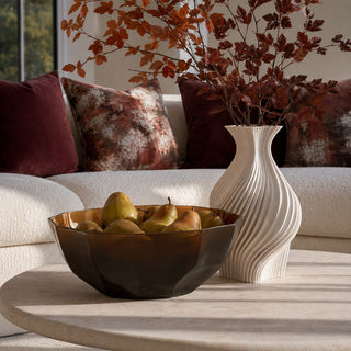 15 Inch Sicilia Amber Glass Bowl filled with pears and styled on a stone coffee table beside a sculptural ivory vase in a warm modern living room.