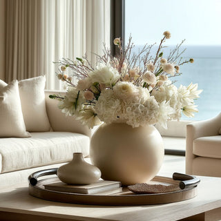 18-inch round mink brown leather tray with alloy handles styled on coffee table with neutral floral arrangement and decorative accents in coastal living room.