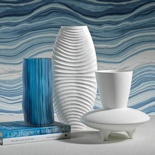 Stlyed with other items, 19.5" tall sculptural white vase with textured wave pattern and made of ceramic.