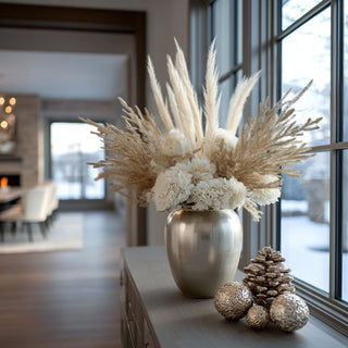 Decorative arrangement with20.5 inch gold glittered bush stem,  pampas grass and white flowers in a metallic vase on a table. The theme is winter decor styling and holiday floral arrangements. 