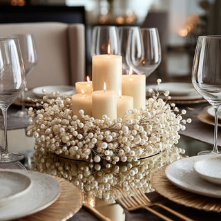 20-inch gold and pearl beaded candle ring styled as a centerpiece on a holiday dining table with glowing pillar candles, glassware, and neutral dinnerware, creating an elegant and inviting seasonal table setting.