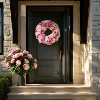 Ultra-realistic 24-inch blush and champagne faux peony wreath styled on a matte black modern front door with limestone exterior facade and soft natural sunlight, luxury spring home decor inspiration for upscale entryways.