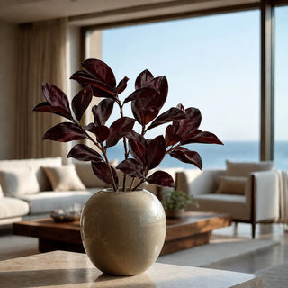 Styled 26 Inch High Artificial Merlot colored magnolia spray stems in a beige ceramic vase placed on a stone table in a modern contemporary decor style coastal home living room 