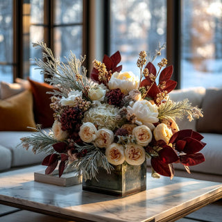 33 Inch Burgundy velvet magnolia leaf spray arranged in a large winter floral display with ivory and champagne blooms in a modern glass vase on a marble coffee table in a luxury Santa Monica-style living room, surrounded by neutral décor and golden hour light.