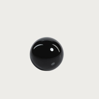 A 4 inch glossy black crystal glass decorative ball/orb styled on a light grey background