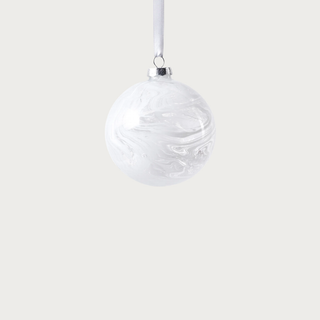 White watercolor glass ornament with satin ribbon displayed on Christmas tree in bright living room – sophisticated winter-white holiday décor accent.