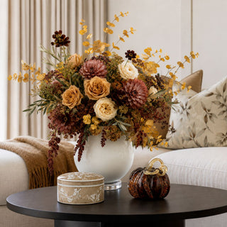 5.5 Inch Small Brown Chinoiserie Lidded Empress Ceramic Box styled on a dark wood coffee table beside a brown handblown glass pumpkin and fall floral arrangement.