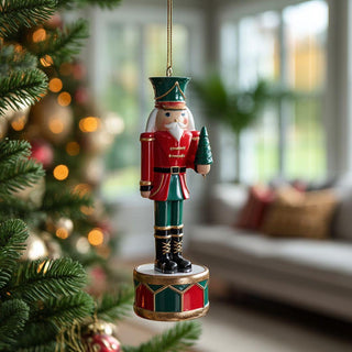 Festive resin nutcracker soldier ornament holding small Christmas tree in red and green with gold accents – elegant handcrafted holiday decoration.