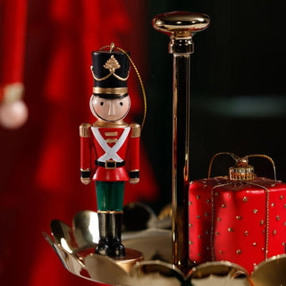 Decorative nutcracker figure with a red suitcase and gold cane on a dark background