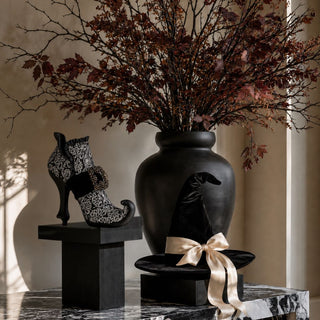 Black and silver rhinestone witch boot styled with black witch hat and dark fall branches for glamorous Halloween decor