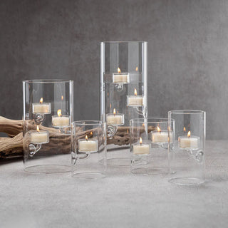 Set of 4 clear glass suspended tea-light holders styled with lit candles grouped at the center of a dining table