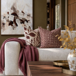 71 Inch Malbec 100% baby alpaca throw blanket draped over a cream sofa with burgundy patterned pillows in a warm modern transitional living room.