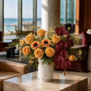 8.25 Inch Polished Alabaster Vase and Candle Holder styled as a floral vessel with peach roses, burgundy orchids and greenery on a stone table.
