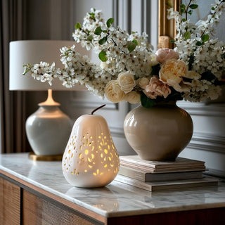White ceramic cutout LED pear emitting a soft glow, styled on a contemporary credenza with neutral décor and floral arrangement