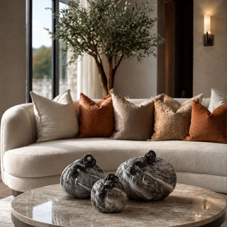 Black and Gray Swirl Glass Pumpkins styled as a trio on a marble coffee table with smoky marbled glass, glossy black stems, neutral upholstery, rust pillows, and warm contemporary fall decor.
