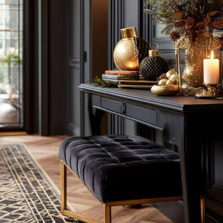 Black console table styled with black velvet and gold decorative tabletop ornaments, candles, and festive greenery in a sophisticated entryway – elegant holiday home décor featuring luxurious textures, metallic accents, and warm ambient lighting.