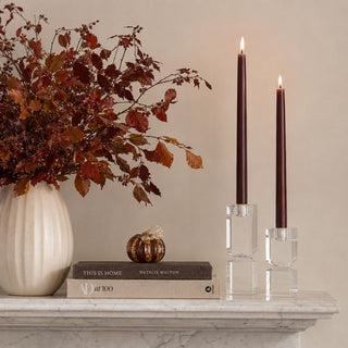3.25 Inch Brown Speckled Glass Pumpkin styled on books beside burgundy taper candles, fall branches, and a cream vase on a marble mantel.