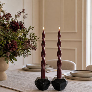 12 Inch Burgundy Twisted Candle Taper Set of 2 styled on a dining table with black marble candle holders, neutral tableware, and a moody floral arrangement
