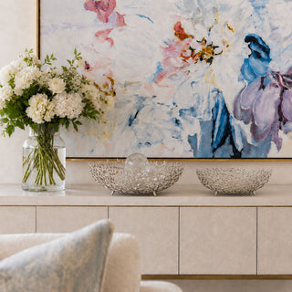 Celine silver decorative bowls styled beneath abstract floral wall art with white floral arrangement in luxury coastal transitional interior