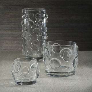 Clear Celeste Tall Vase/Hurricane shown with coordinating clear glass vessels, featuring raised circular glass detail and reflective texture.
