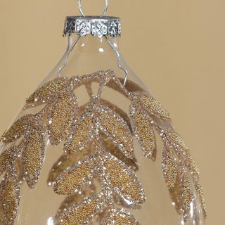 Close-up of gold beaded leaf design on clear glass ornament – refined holiday decoration for modern and traditional Christmas interiors.