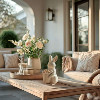 Concrete bunny spring décor styled on a covered porch with soft florals and neutral accents, showcasing an elevated seasonal decorative bunny perfect for indoor styling or protected outdoor spaces.