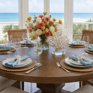 white coral napkin rings styled on blue linen napkins at luxury coastal dining table with ocean view and colorful floral centerpiece