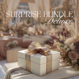 Decorative gift box with a gold bow on a table with flowers and the text 'Surprise Bundle Deluxe'.