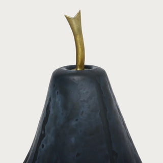 Close-up of a deep blue glass pear sculpture showing its slender curved brass stem and dark textured glass surface.