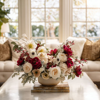 Elegant faux floral arrangement with red and cream roses, anemones, and greenery displayed in neutral ribbed ceramic vase on marble coffee table in bright living room – sophisticated holiday or year-round centerpiece for modern home décor