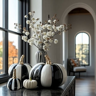 Entryway console styled with 7.25-inch black and white striped ceramic pumpkin with gold-colored stem, black striped vase, and white floral arrangement.