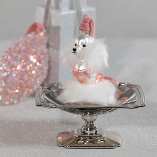 Decorative dog figurine on a silver stand with a pink hat against a glittery background