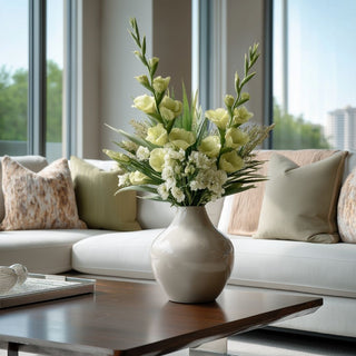 Tall floral arrangement featuring green True Bloom real touch gladiolus stems layered with white florals and airy greenery, styled in a ceramic vase on a modern coffee table in a light-filled living room.