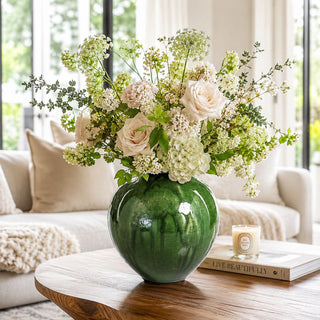 A softly layered living room moment featuring abundant florals, rich green ceramic, and warm natural light—designed to feel fresh, elevated, and effortlessly lived in.