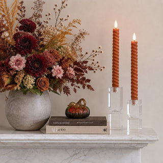 3 Inch Green & Amber Glass Pumpkin styled on books beside ember spiral LED taper candles, crystal candleholders, fall florals, and a marble mantel.