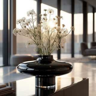 Handmade luxury onyx opal black glass vase with glossy sculptural design displayed on modern console table filled with delicate white florals, sunlight streaming through floor-to-ceiling windows in contemporary living room – luxurious minimalist home décor styling inspiration.