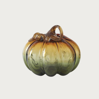Large ombre green and amber glass pumpkin measuring 7.5 inches high by 9 inches wide with ribbed glass and a curled brown stem.