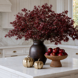 Large dark brown mango wood vase styled with burgundy fall branches on a marble kitchen island with soft gold pumpkins and woven accents.