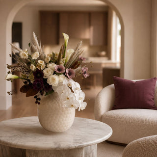 11.75 Inch Large Taupe Frosted Cut Glass Vase styled on a marble coffee table with cream florals, orchids, burgundy blooms, pampas, and a warm neutral interior.