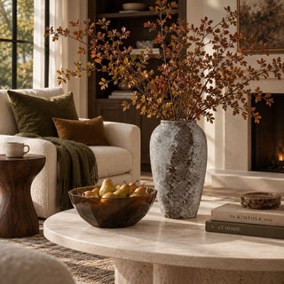 Tuscan vase with autumn branches on a stone coffee table near a fireplace