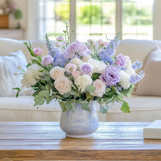 Romantic pastel floral arrangement featuring True Bloom Floral stems including light purple buttercups, roses, lisianthus, and delphinium in a soft blue ceramic vase, styled in a luxury living room with natural light. True Bloom Floral, True Bloom, Real Touch. Flower Arrangement, Third & Main, Home Decor, Decor 