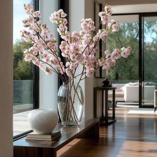 Four 41-inch True Bloom light purple real touch blossom stems arranged in a tall glass vase on a modern contemporary console in a luxury Santa Monica home with floor-to-ceiling windows and bright natural light.