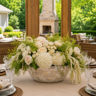 A luminous mother of pearl planter overflowing with layered white florals and cascading greenery, creating an elegant centerpiece for refined outdoor entertaining.